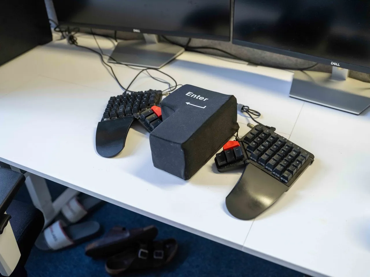  Auf einem Schreibtisch im IDA-Office ist neben einer schwarzen Tastatur ein übergroßer Enter-Knopf aus Stoff zu sehen, der nur per Faustschlag bedient werden kann.