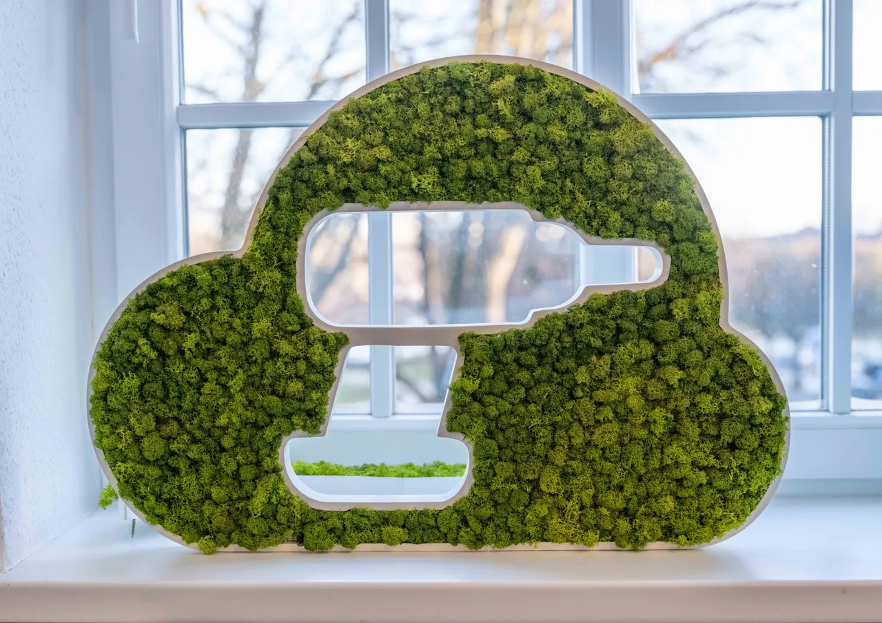 In einer Fensterbank steht das IDALABS-Logo als grünes Moosbild: Das Logo stellt eine Wolke dar, aus der die Silhouette eines Bohrers ausgeschnitten ist.